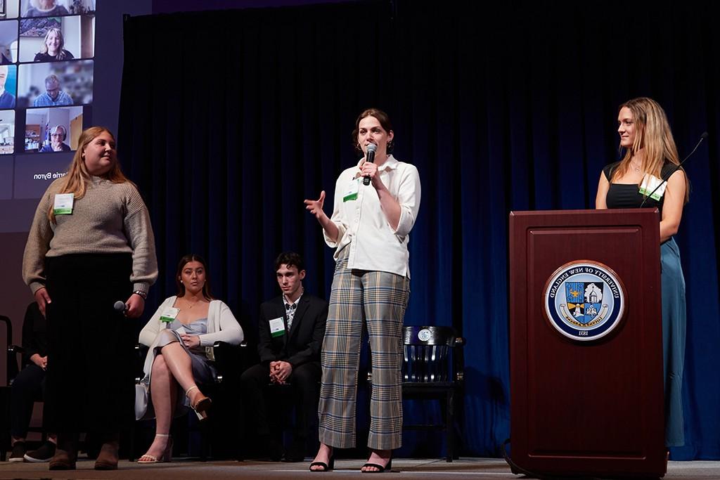 Five presenters at the innovation celebration stand and sit on a stage