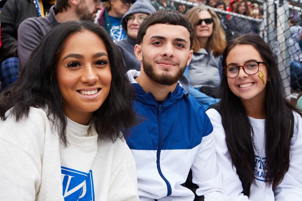 Three U N E students at a U N E football game