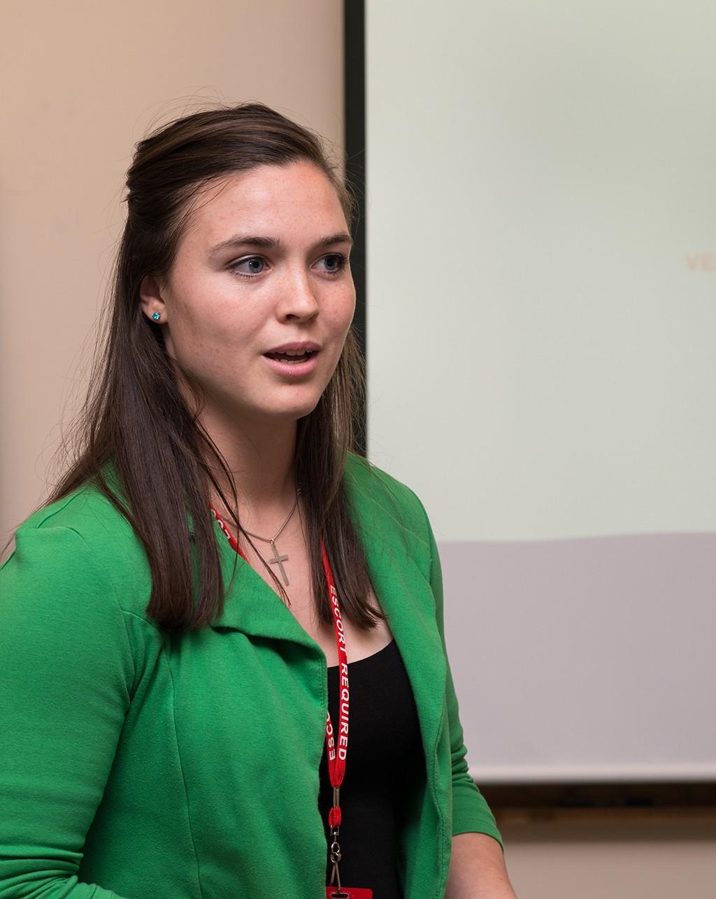 Image of student in green shirt standing in front of class