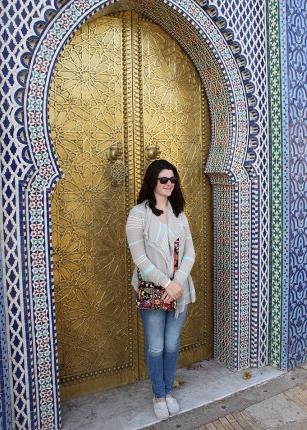 A student standing in front of a gilded door in Morocco