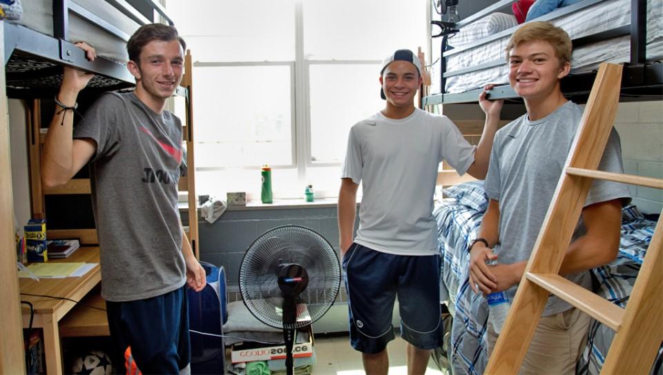 Three students standing in their dorm room