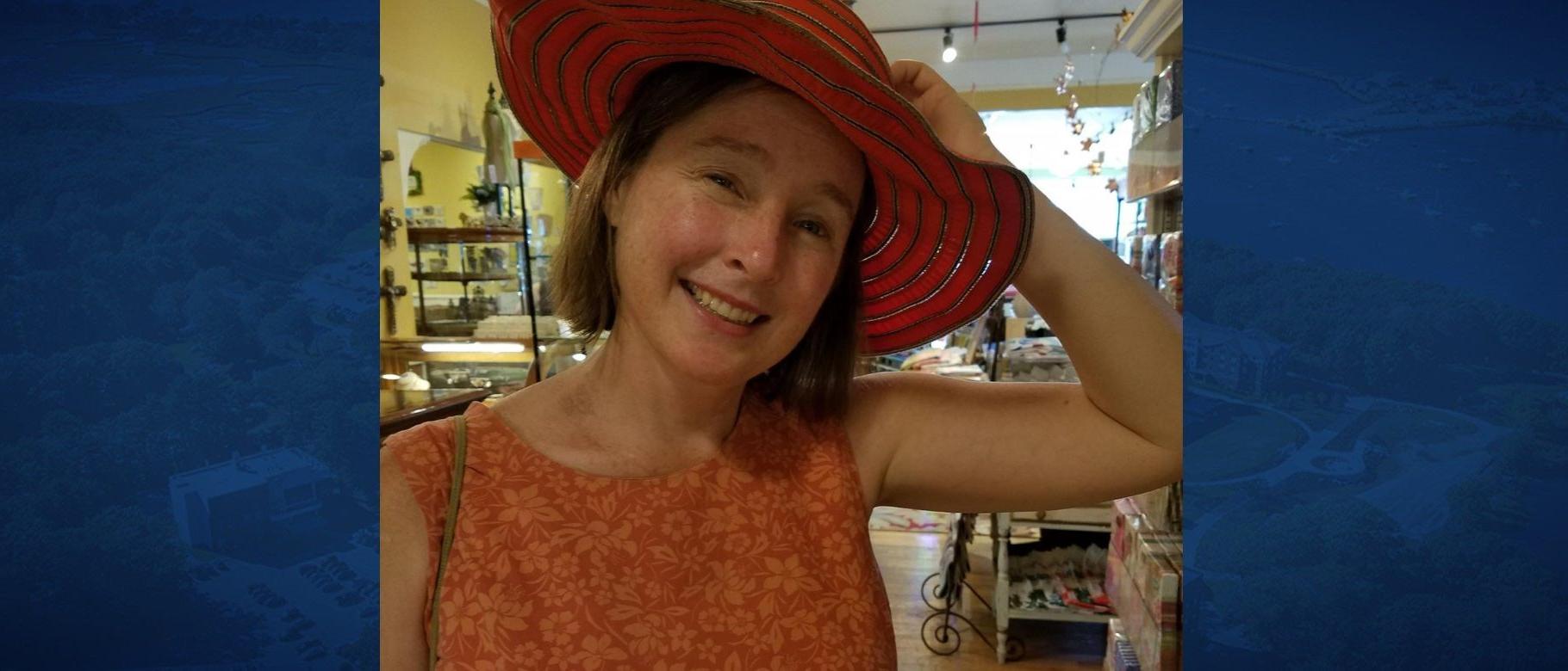 Susan McHugh poses wearing a red hat