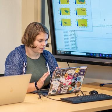 A student sits at a table while working on a lap top 