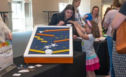 A child plays with an adaptive toy at a display table