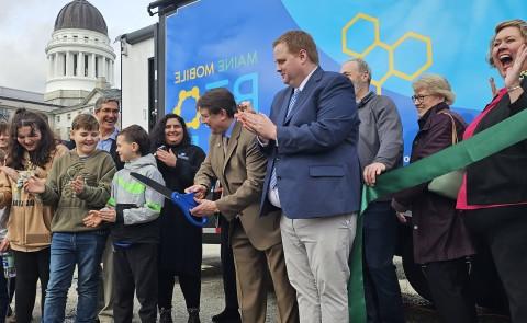 A crowd cheers at a ribbon cutting ceremony 