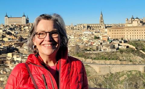 A woman smles for a photo in front of a countryside Spanish city 