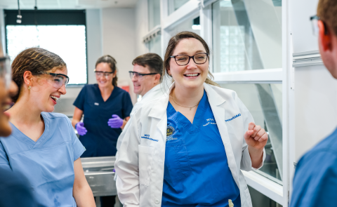 A medical student smiles with her classmates in a UNE lab